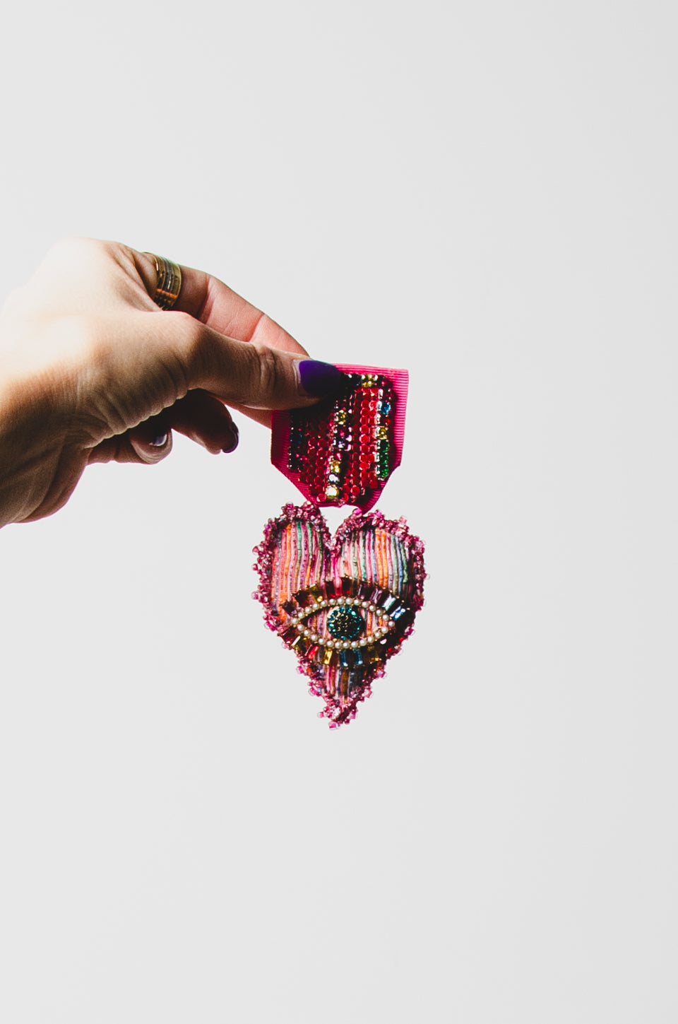 Spilla a forma di medaglia con cuore rosa ricamato a mano con pietre e occhio centrale